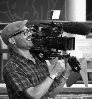 David Jarvis, Filmmaker at Three Word Agency, holding a film camera and smiling